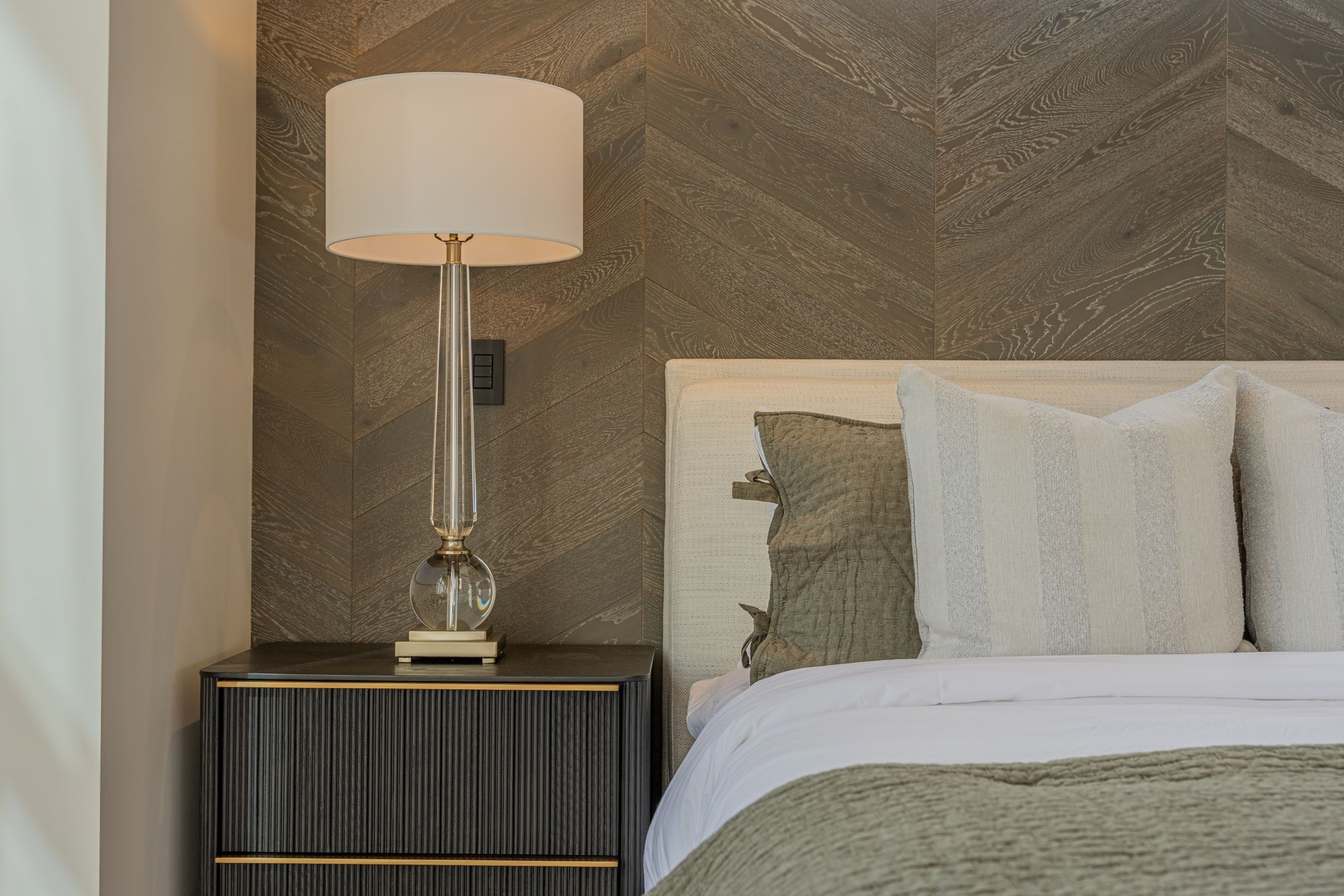 A bedside, the lamp and the oak wall behind the bed