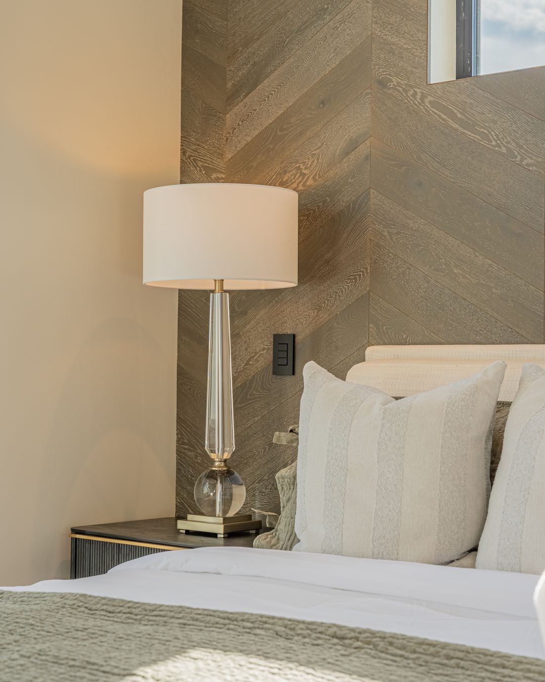 A bedside lamp and the oak wall behind the bed