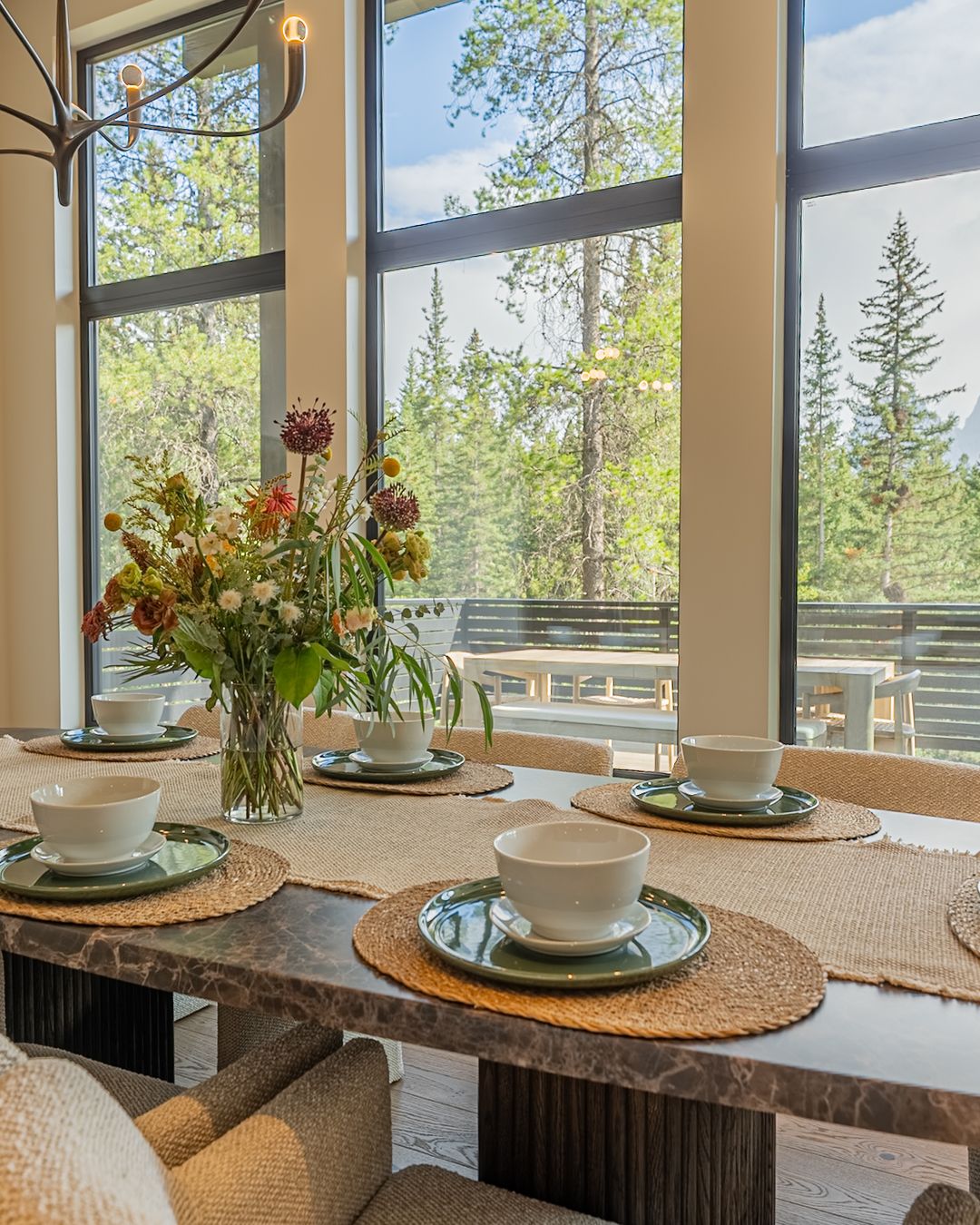The dining table set, flowers in the middle, the windows behind