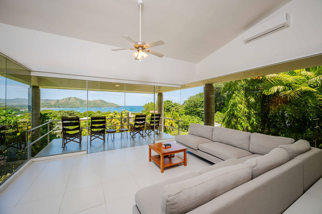 Living room opening to the terrace, bay visible through glass walls