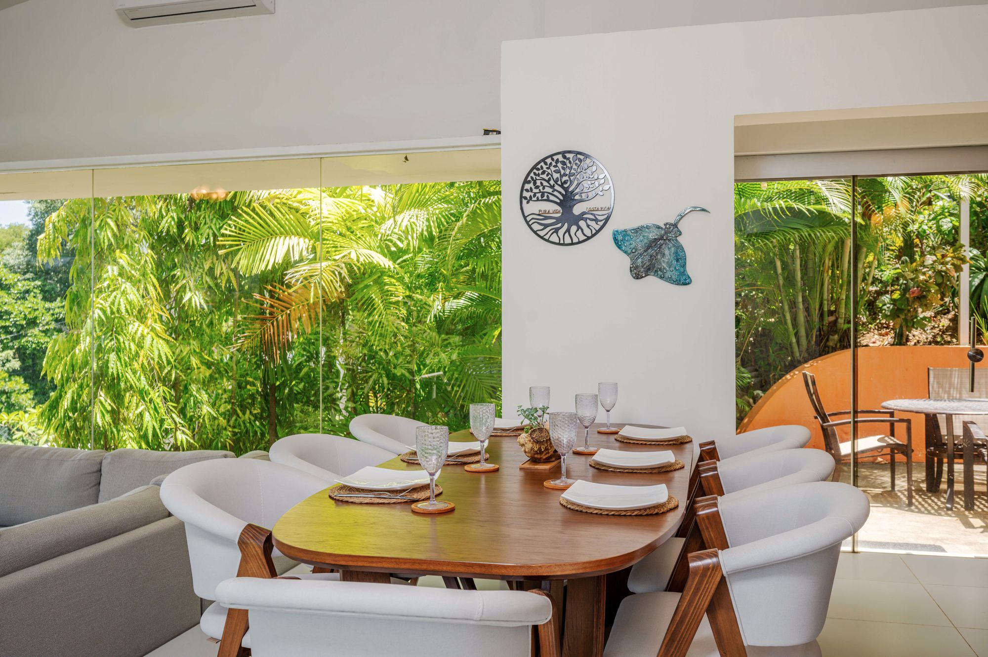 The table set before arrival, the garden through the glass
