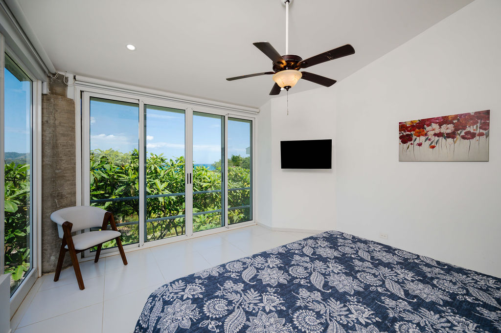 Bedroom corner with sliding glass doors and ocean glimpse