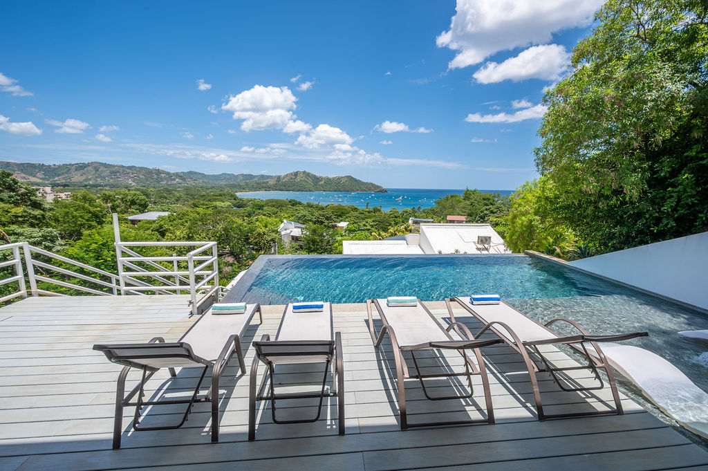 Infinity pool with loungers, looking out across the bay