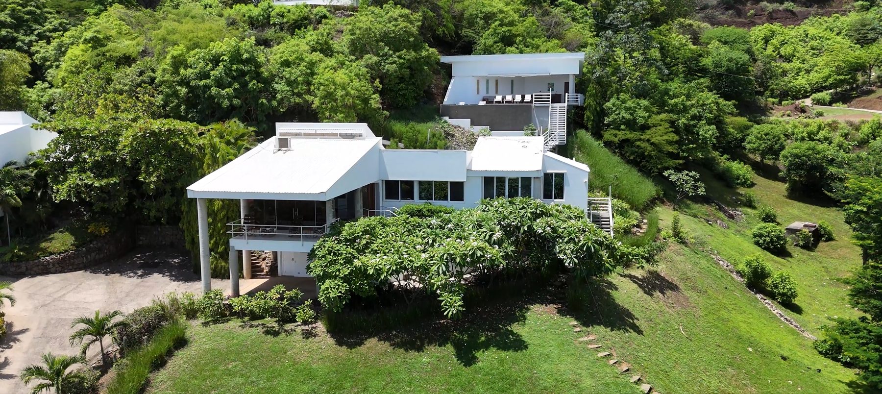 Vista Bahia exterior. A white villa on a hillside above Playas del Coco, framed by tropical greenery, with the Pacific bay in the background.